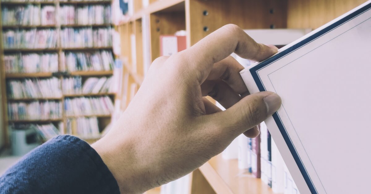 図書館の本棚から本を取る手