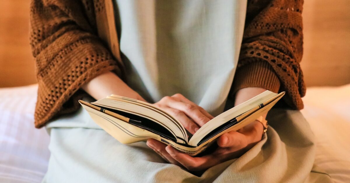 膝の上で本を読む女性の手元