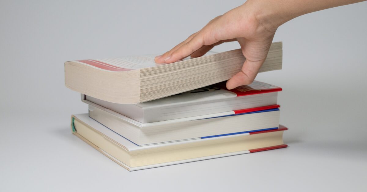 積まれた本の上から本を取る手