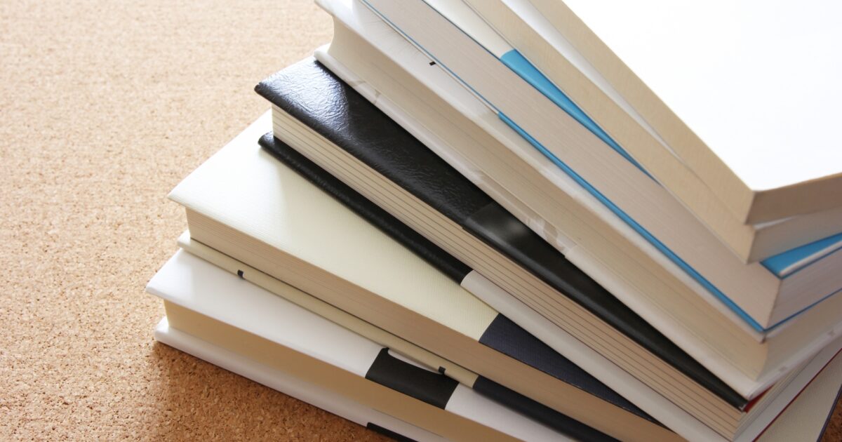 机の上に積まれた白い表紙の本の山